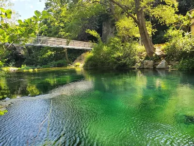 a bridge over a river with green water at Renovated and air-conditioned 2-bedroom apartment with terrace in Saint-Paul-de-Fenouillet