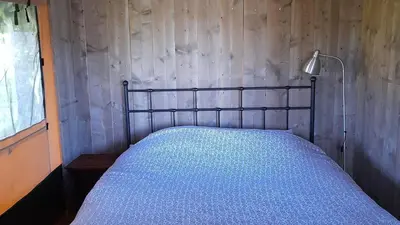 a bed in a room with a wooden wall at Lodge Holidays - Les Sapins in Camurac