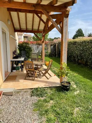 a patio with a table and chairs under a wooden pergola at House in a rural village surrounded by vineyards in Leuc