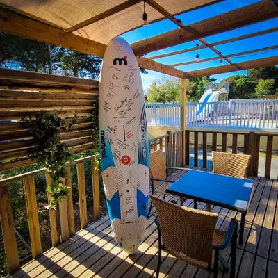 a surfboard on a deck with a table and chairs at Cap du Roc in Port-la-Nouvelle