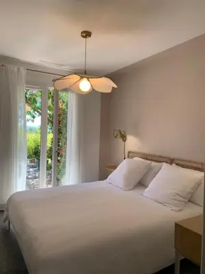 a bedroom with a white bed with a ceiling fan at Le chant des cigales in Villemoustaussou