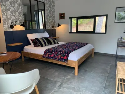 a bedroom with a bed and a table and a chair at Le chant des cigales in Villemoustaussou