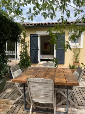 a wooden table and chairs in front of a house at Le chant des cigales in Villemoustaussou