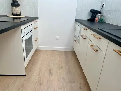 a kitchen with white cabinets and a wooden floor at T2 sous les toits, entre gare et centre-ville, Grands buffets in Narbonne