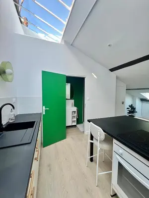 a kitchen with a green door and a black counter top at T2 sous les toits, entre gare et centre-ville, Grands buffets in Narbonne