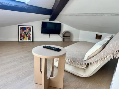 a bedroom with a bed with a table and a tv at T2 sous les toits, entre gare et centre-ville, Grands buffets in Narbonne