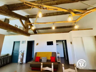 a living room with wooden beams and a couch at Nore & nature in Pradelles-Cabardès