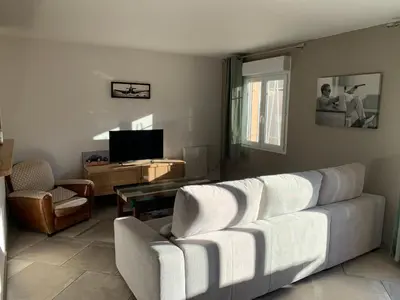 a living room with a white couch and a television at La Petite Villa du Soleil in Lavalette