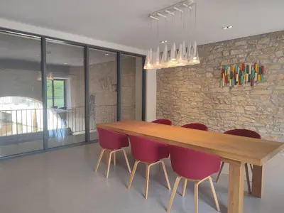 a dining room with a wooden table and red chairs at Séjour d'exception au Moulin de la Vernède avec piscine, ruisseau, climatisation et parking in Conques-sur-Orbiel