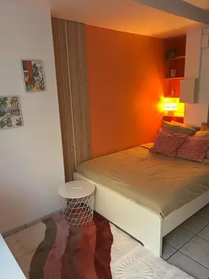a bedroom with a bed with an orange wall at Studio Cosy proche Cité Centre WiFi in Carcassonne