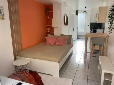 a bed in a small room with an orange wall at Studio Cosy proche Cité Centre WiFi in Carcassonne