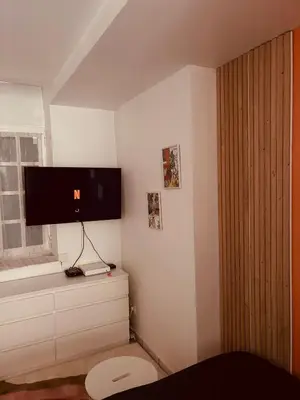 a bedroom with a tv on the wall and a toilet at Studio Cosy proche Cité Centre WiFi in Carcassonne