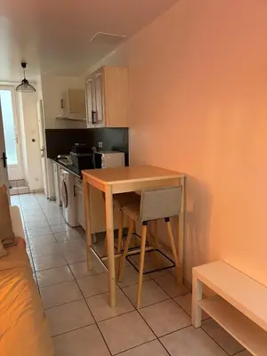 a small kitchen with a wooden table and a chair at Studio Cosy proche Cité Centre WiFi in Carcassonne