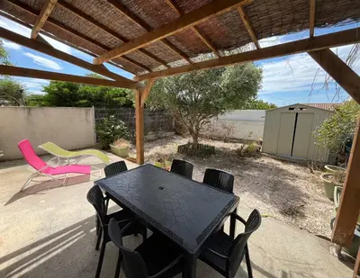 a patio with a table and chairs under a pergola at Villa Vinassan in Vinassan
