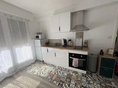 a kitchen with white cabinets and a tile floor at Loni in Carcassonne