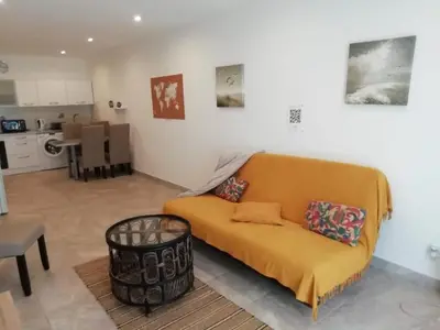 a living room with an orange couch and a kitchen at Charming house in a great location in Narbonne