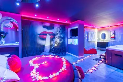 a bedroom with a large red bed with a painting of lips at Secret Night Pamiers in Pamiers