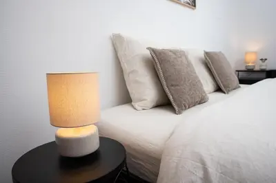a white bed with pillows and a lamp on a table at Pure Canigou House An Authentic and Charming Town house with 3 bedrooms in Montalba-le-Château