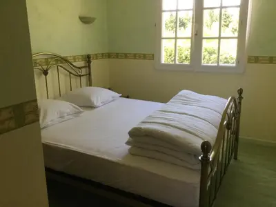 a bedroom with a bed with white sheets and a window at Gites De La Grasse in Carcassonne