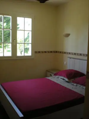 a bedroom with a bed with pink sheets and two windows at Gites De La Grasse in Carcassonne