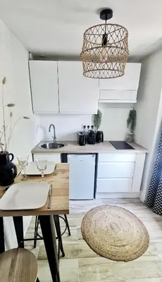 a kitchen with white cabinets and a table and a rug at N3-Barbacane-Pieds Cité-Clim mobile in Carcassonne