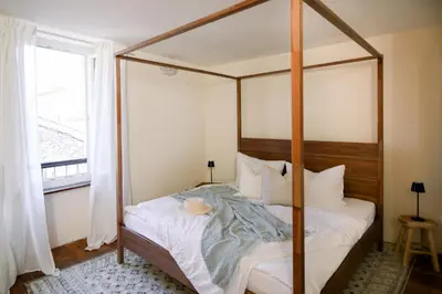 a bedroom with a canopy bed and a window at Steinhaus mit Dachterrasse und Badefluss in Ribaute