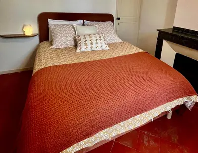 a bedroom with a large bed with a red comforter at Le Gîte d'Oré - 2 Chambres et Climatisation in Carcassonne