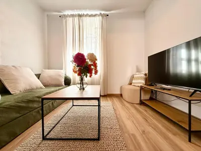 a living room with a green couch and a television at Le Gîte d'Oré - 2 Chambres et Climatisation in Carcassonne