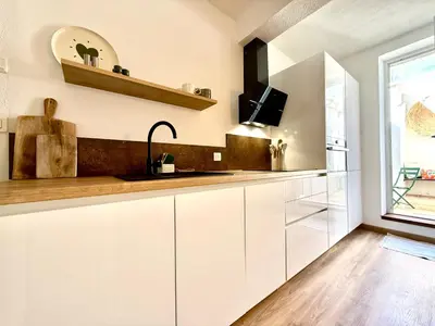 a kitchen with white cabinets and a window at Le Gîte d'Oré - 2 Chambres et Climatisation in Carcassonne