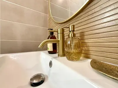 a bathroom sink with two bottles and a mirror at Le Gîte d'Oré - 2 Chambres et Climatisation in Carcassonne