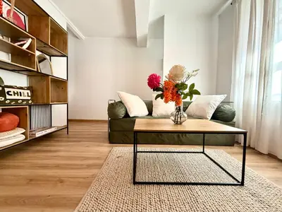 a living room with a couch and a table with flowers at Le Gîte d'Oré - 2 Chambres et Climatisation in Carcassonne