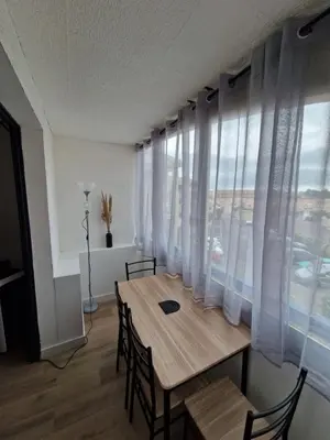 a dining room table with chairs and a large window at La Porte de la Mer in Port-la-Nouvelle