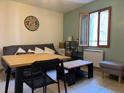 a living room with a table and a clock on the wall at T2 contemporain centre ville in Narbonne