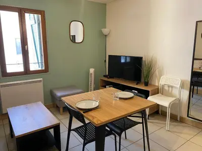 a living room with a table and chairs and a television at T2 contemporain centre ville in Narbonne
