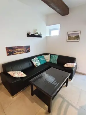 a black leather couch with a coffee table in a living room at Château de Prax Viel - piscine et mini ferme, climatisé in Lagrasse