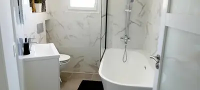 a white bathroom with a shower and a toilet at Chez Jacques in Port-la-Nouvelle