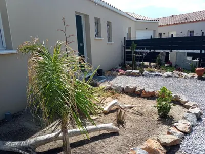 a garden with a palm tree and rocks in front of a house at Chez Jacques in Port-la-Nouvelle