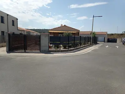 a fence in a parking lot with a building at Chez Jacques in Port-la-Nouvelle