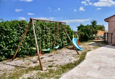 a swing set in a yard next to a hedge at Villa avec piscine chauffée et jacuzzi in Ouveillan
