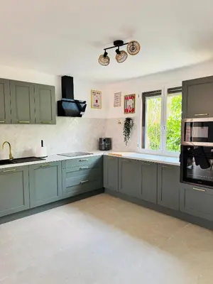 a large kitchen with green cabinets and a window at Villa avec piscine chauffée et jacuzzi in Ouveillan