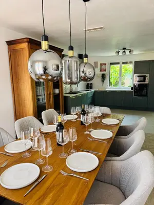 a long wooden table with white plates and wine glasses at Villa avec piscine chauffée et jacuzzi in Ouveillan