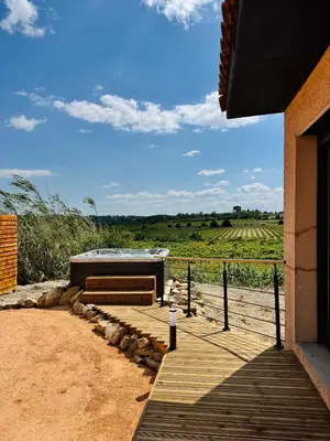 a hot tub on a wooden deck next to a house at Villa avec piscine chauffée et jacuzzi in Ouveillan