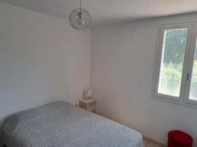 a white bedroom with a bed and a window at Villa avec piscine à Montolieu in Montolieu