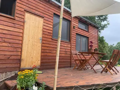 a house with a wooden deck with a table and an umbrella at Tiny House en bois in Cubières-sur-Cinoble