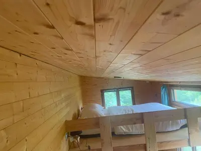 a log cabin with a bed in a room at Tiny House en bois in Cubières-sur-Cinoble