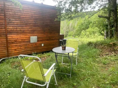 two chairs and a table in the grass at Tiny House en bois in Cubières-sur-Cinoble