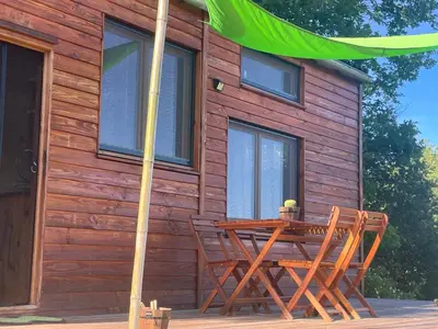 a wooden cabin with a table and chairs in front of it at Tiny House en bois in Cubières-sur-Cinoble