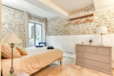 a bedroom with a bed and a stone wall at Au Pied de la Cité - Terrasse - Climatisation - Wifi in Carcassonne