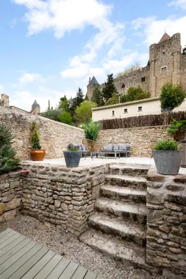 a stone wall with stairs in front of a castle at Au Pied de la Cité - Terrasse - Climatisation - Wifi in Carcassonne
