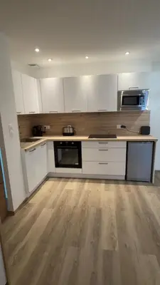 a kitchen with white cabinets and a wooden floor at Le petit narbonnais in Narbonne